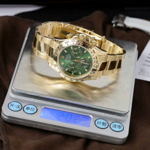 a gold watch with green face and a green seal
